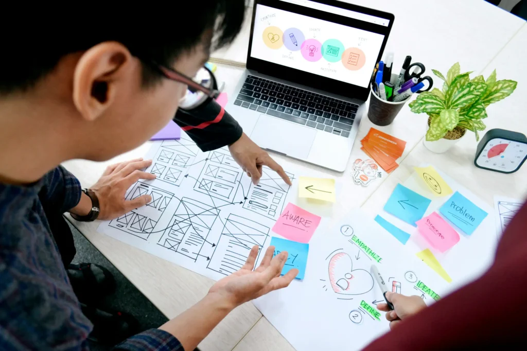 Web designer comparing wireframes and website layout options at a laptop